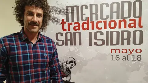 El concejal de festejos, Iv&aacute;n P&eacute;rez, junto al cartel promocional del Mercado Tradicional de San Isidro