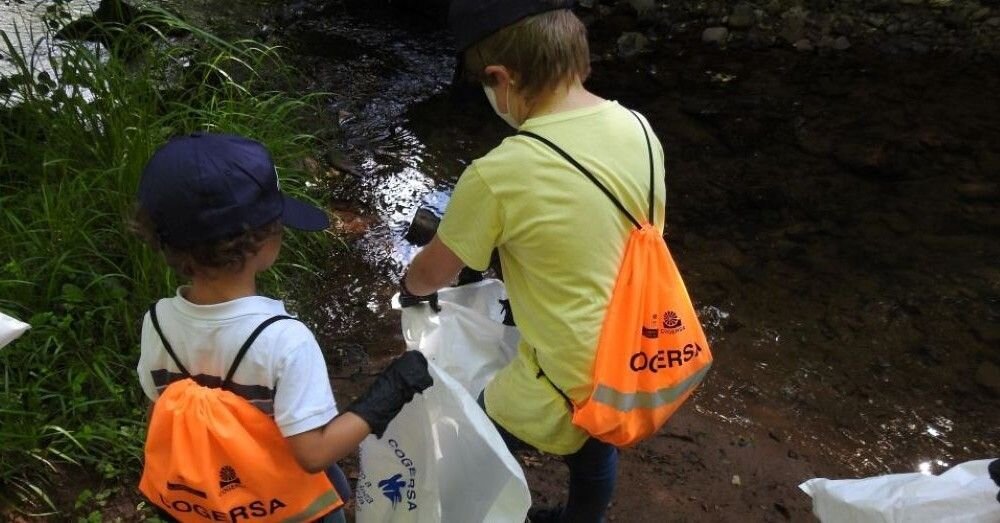 Niños voluntarios limpiando una ribera de un río.