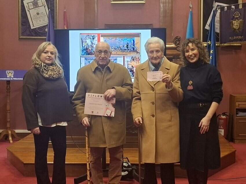 Rocío Vega, concejala y Lucía Llera, de Acosevi, entregan el premio a la familia Hevia Noriega.